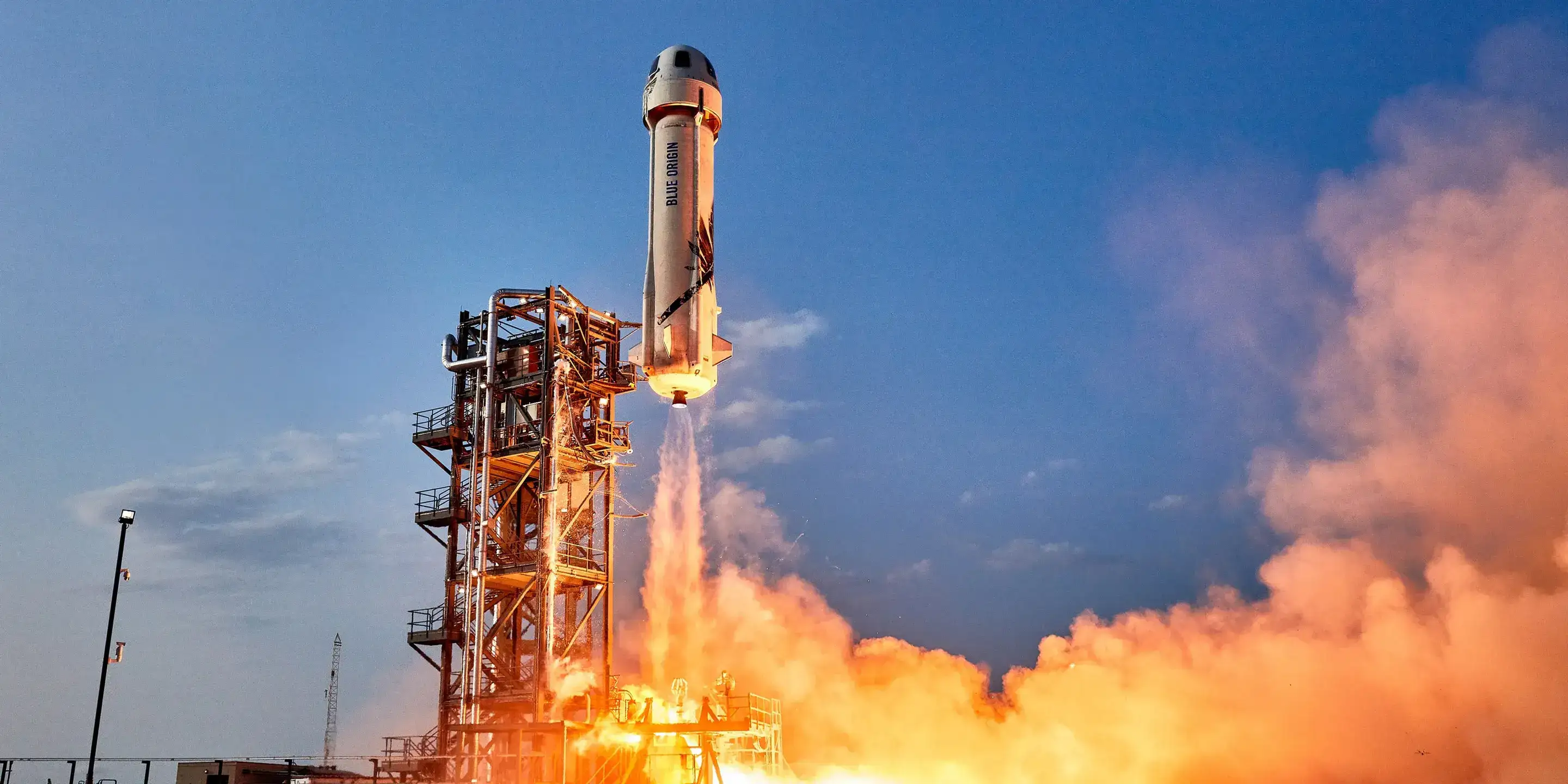  Blue Origin’s New Shepard Rocket launch at dusk, with vibrant clouds of exhaust and a clear sky